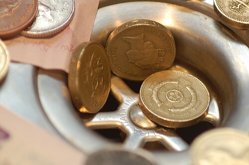 Pound coins going into a drain.